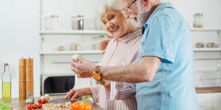 Elderly Couple Preparing a Meal Together While Smiling in a Shared Kitchen at an Assisted Living Facility